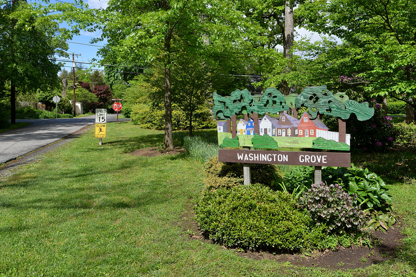 The Washington Grove welcome sign — hand-painted wooden houses and trees